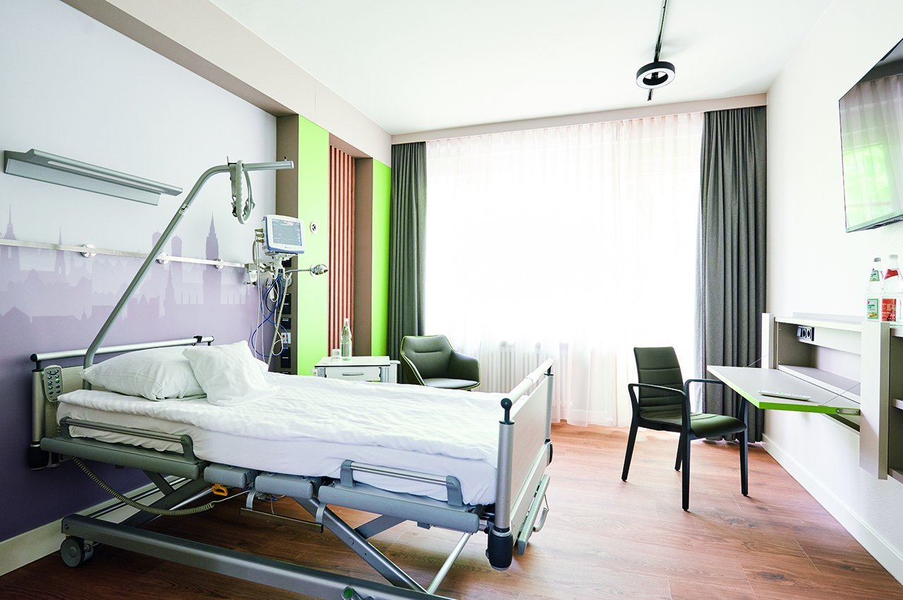 Ein Ein-Bett-Zimmer der Augustinum Klinik Wahlleistungsstation mit einem Fernseher und einem Tisch