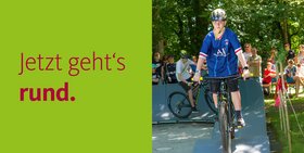 Ein Junge fährt auf einem Pumptrack mit einem Fahrrad. Zu lesen ist, jetzt geht´s rund