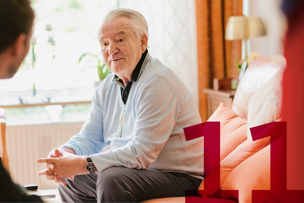 Ein Senior sitzt in einer Wohnung und unterhält sich