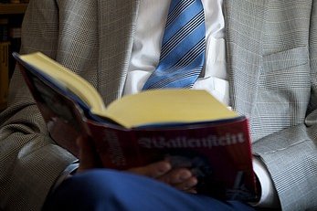 Aufgeschlagenes Buch auf dem Schoß eines Mannes