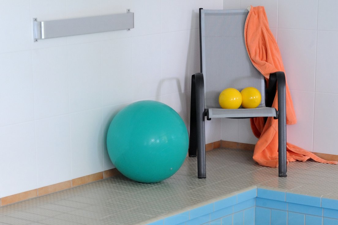 Gymnastikbälle und Stuhl am Rand eines Schwimmbeckens