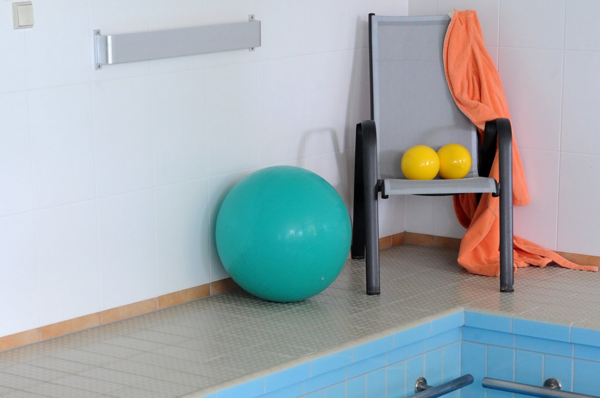 Gymnastikbälle und Stuhl am Rand eines Schwimmbeckens