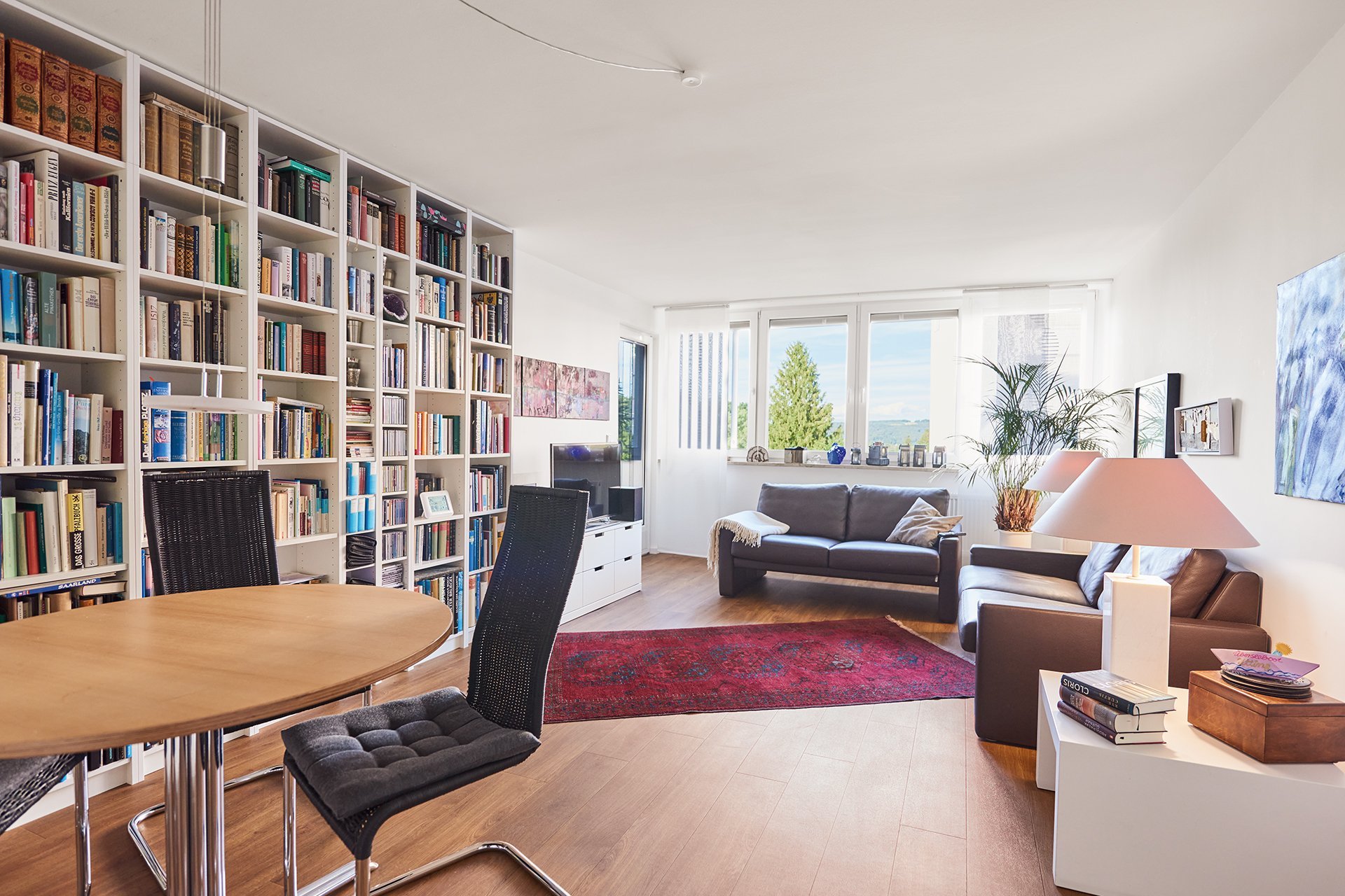 Eine Wohnung mit Sitzmöglichkeiten und einem großen Bücherregal
