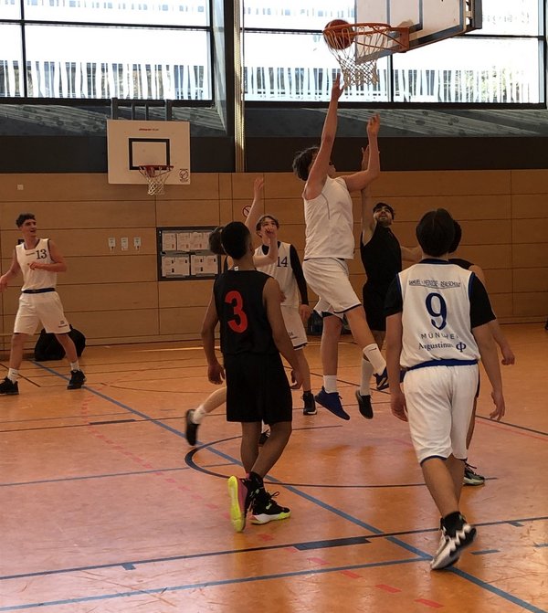 Schüler der Samuel-Heinicke-Realschule spielen in einer Sporthalle Basketball. Einer der Schüler wirft einen Korb. 
