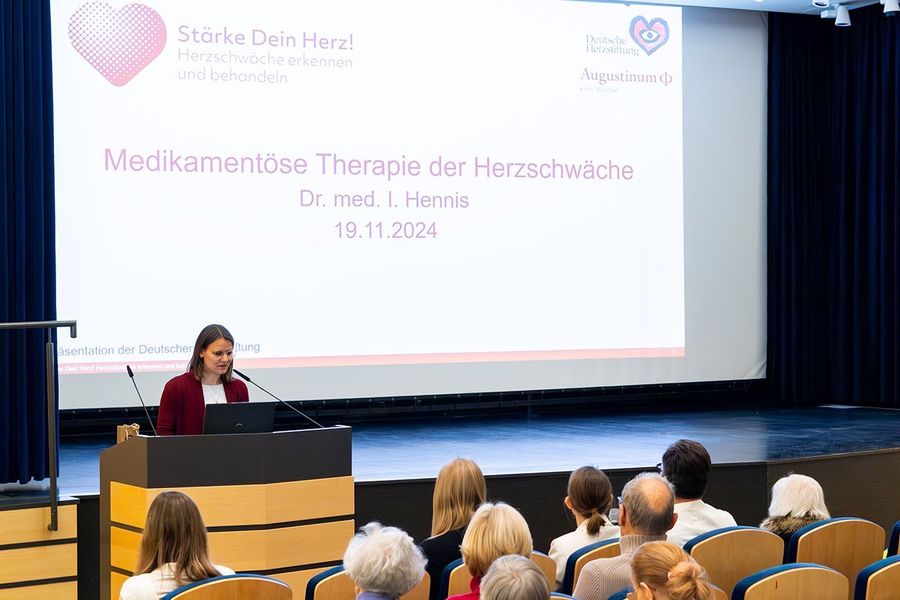 Dr. Irina Hennis steht vor dem Publikum im Theatersaal und hält einen Vortrag zum Thema "Medikamentöse Therapie der Herzschwäche"