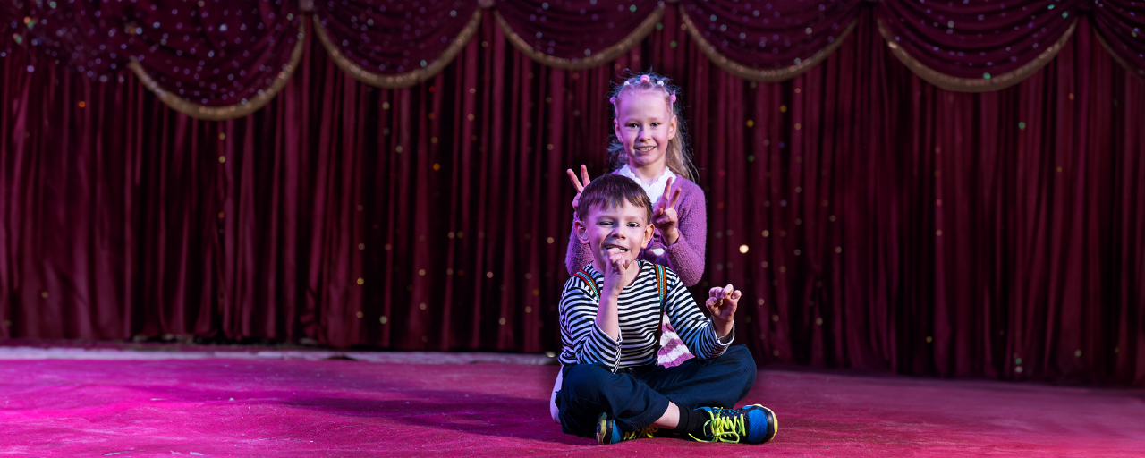 Zwei Kinder sitzen in einem Zirkus auf dem Boden