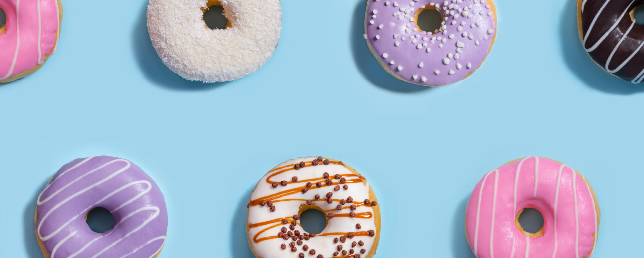 Mehrere bunte Donuts auf einem hellblauen Hintergrund