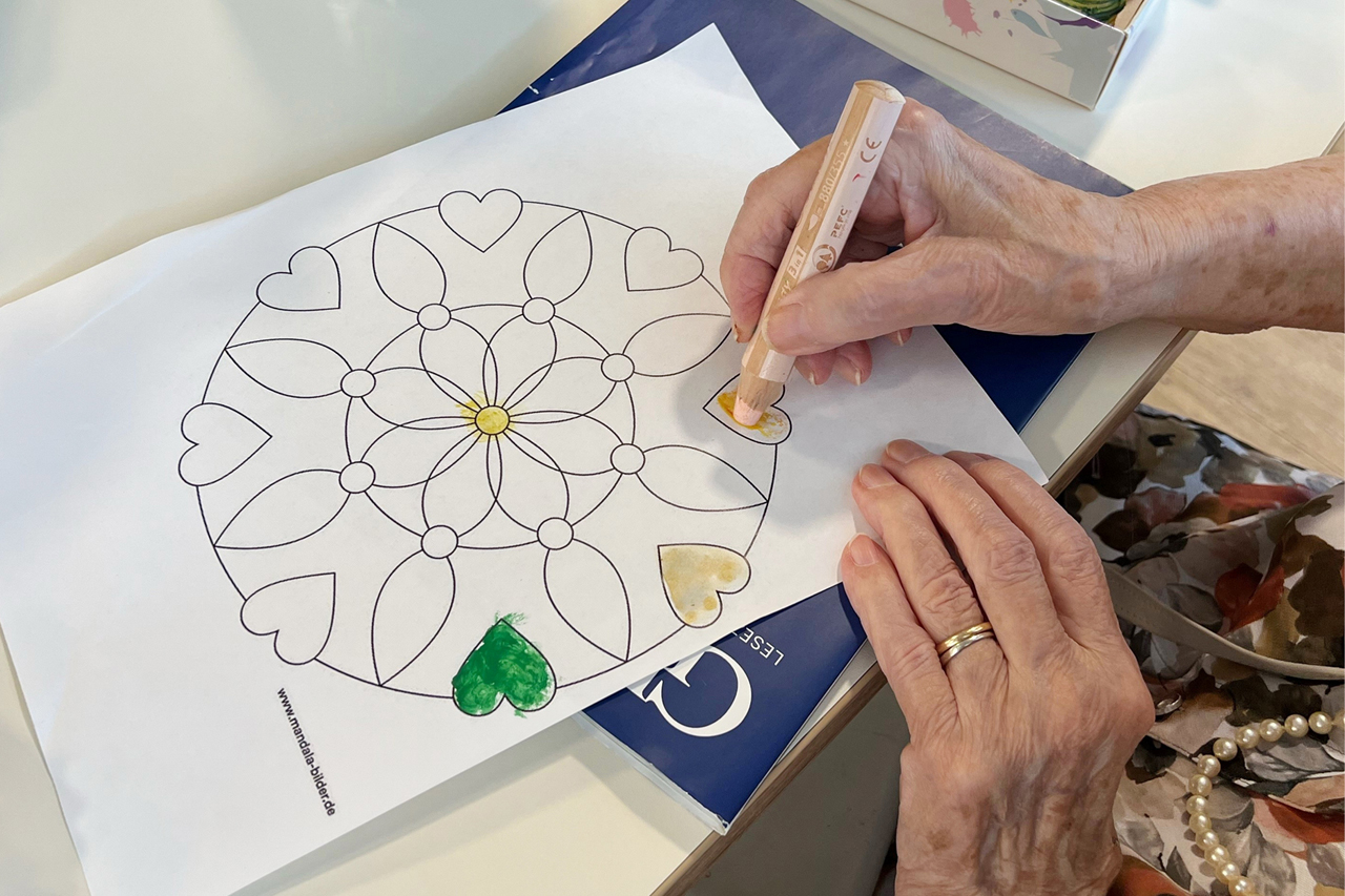 Eine Seniorin malt ein Mandala aus