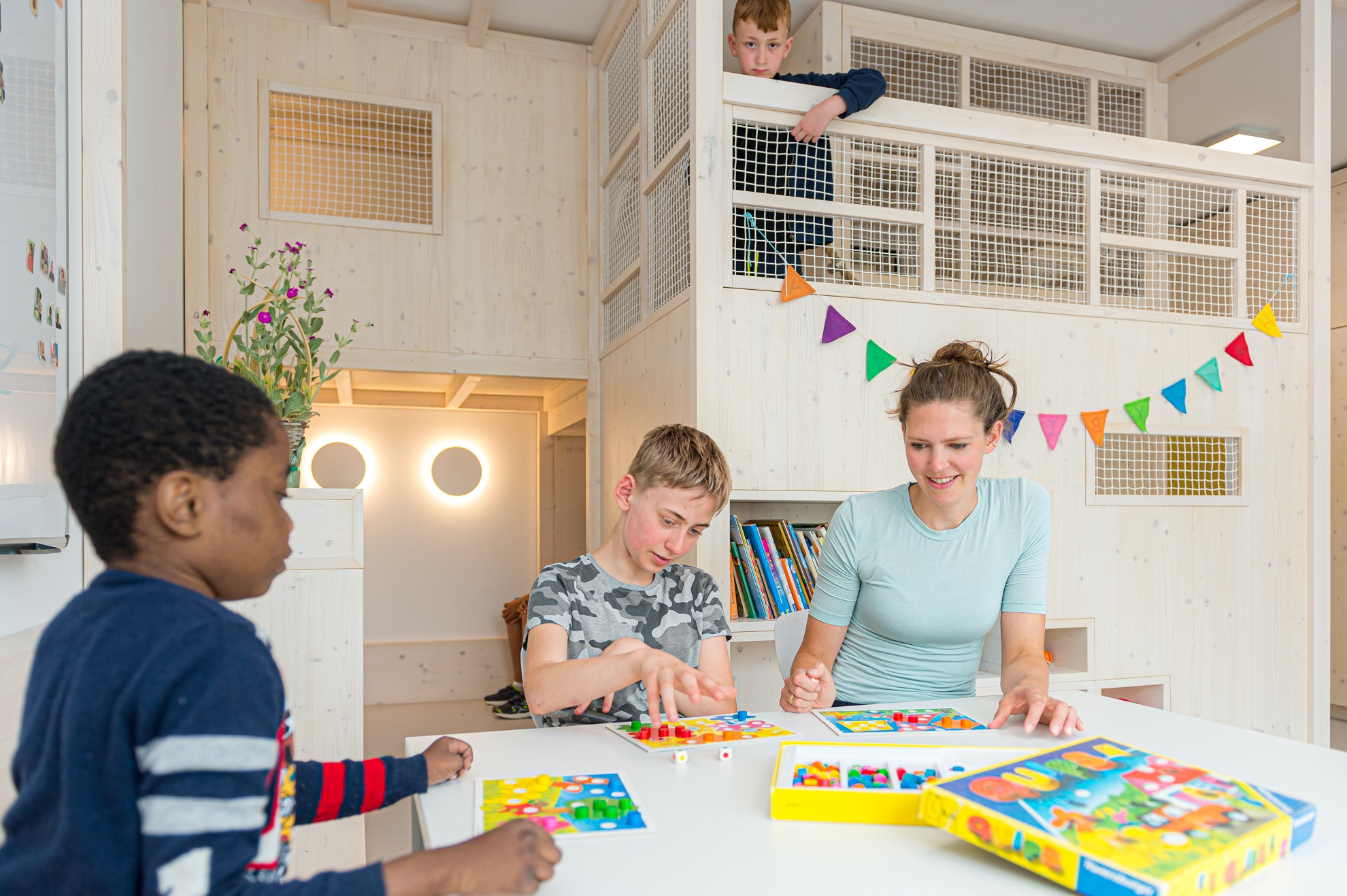 Kinder spielen gemeinsam mit einer Mitarbeiterin ein Brettspiel